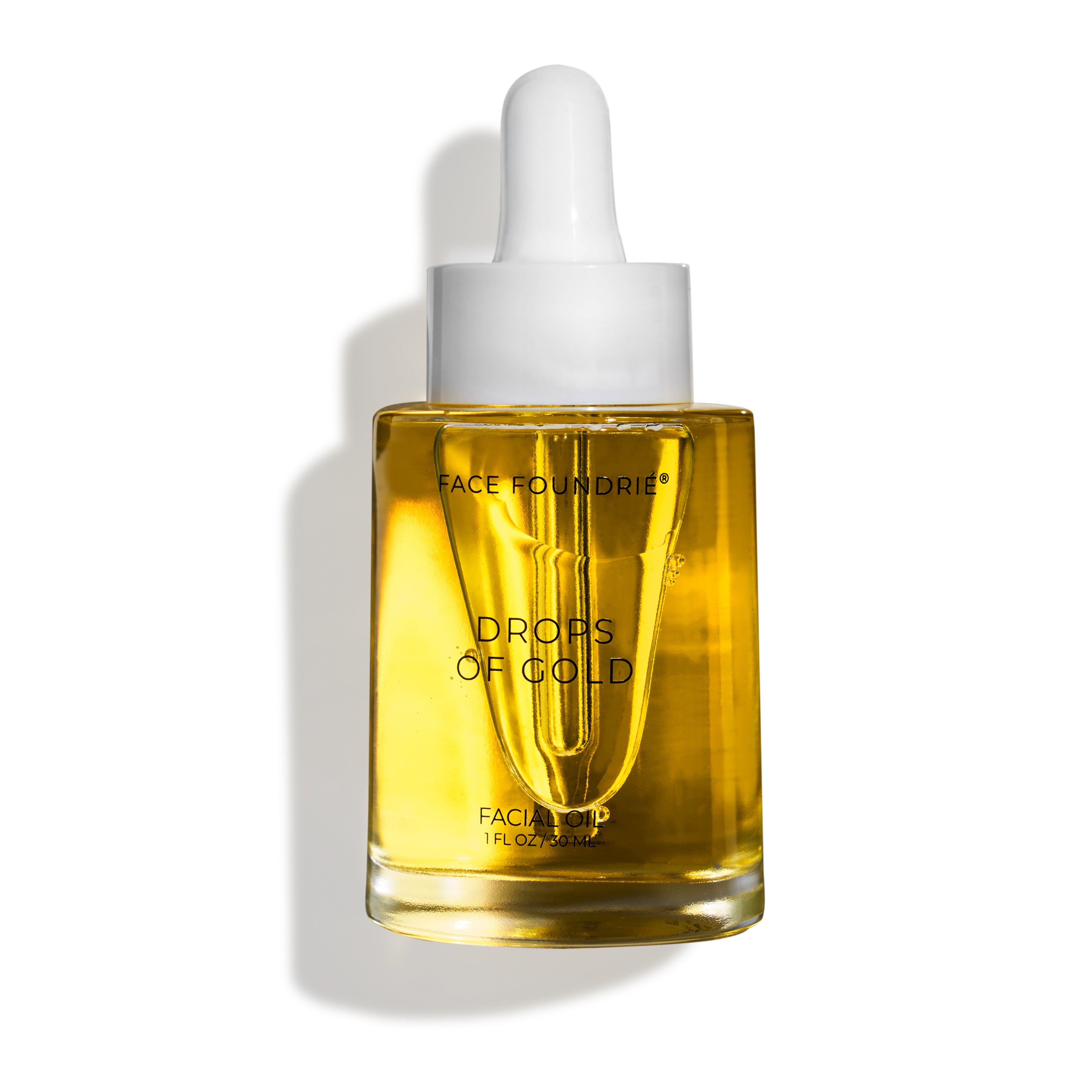 FACE FOUNDRIÉ Drops Of Gold facial oil dropper bottle on a warm, glowy background