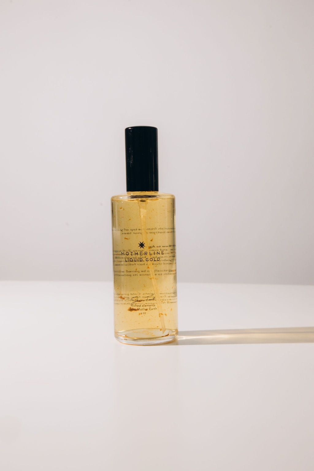 Motherline Liquid Gold spray bottle on a gold-toned background