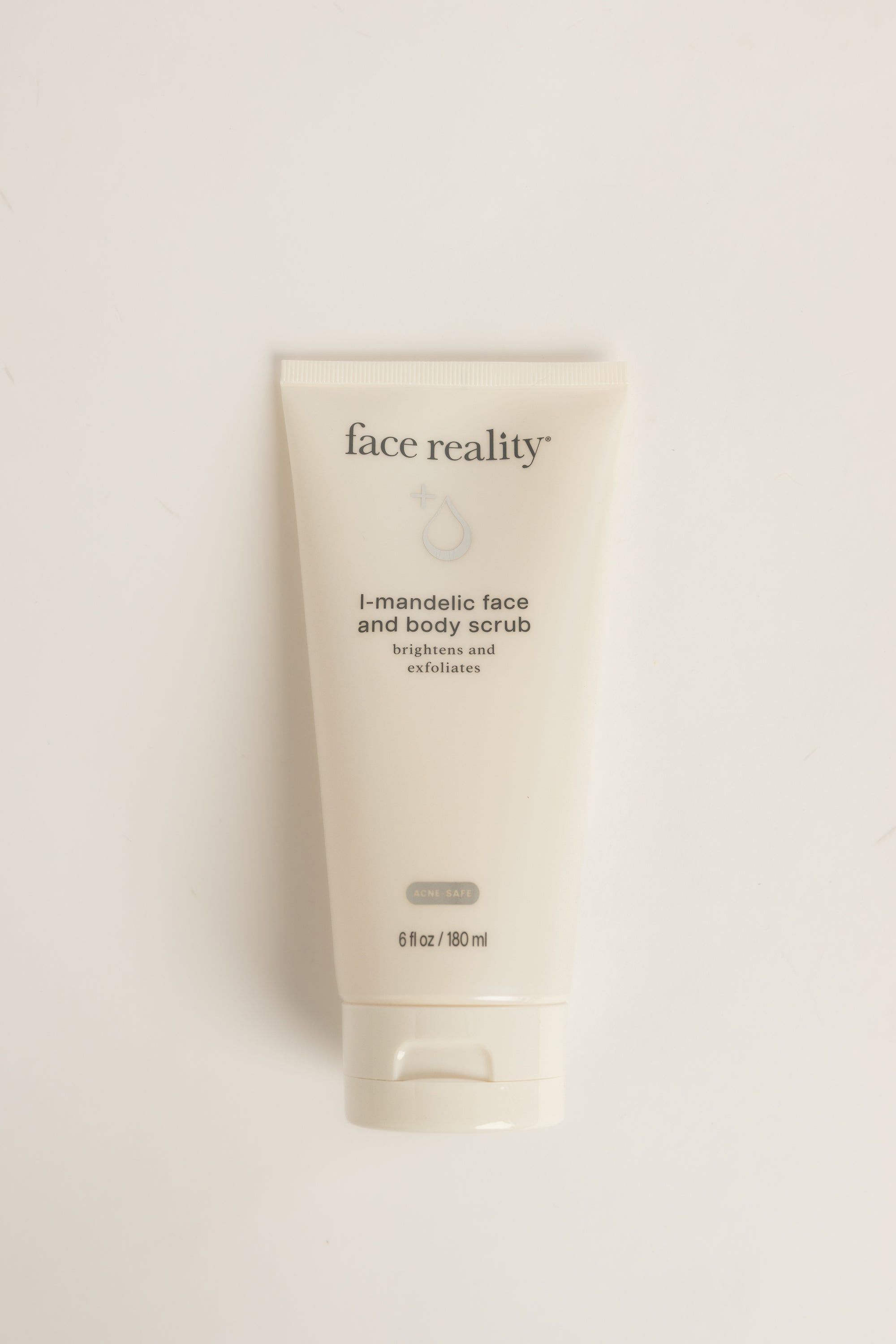 Cream-colored Face Reality L-Mandelic Face and Body Scrub tube with dark text, standing upright on a light background, net weight 6 fl oz (180 ml)